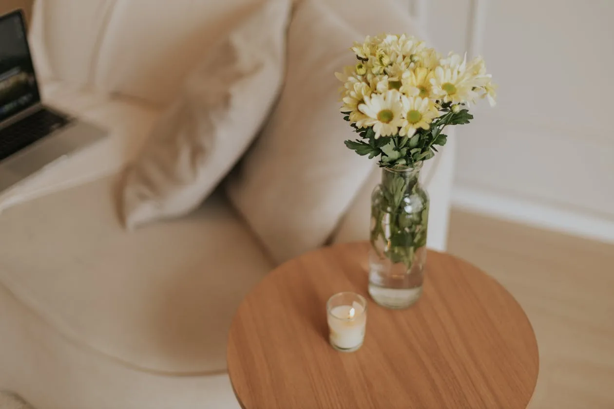 A cosy minimalist interior with fresh flowers and a candle on a wooden table
