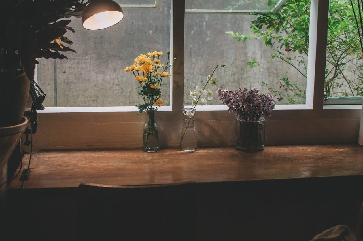 Flowers in vases with a warm lamp on a windowsill in a home interior