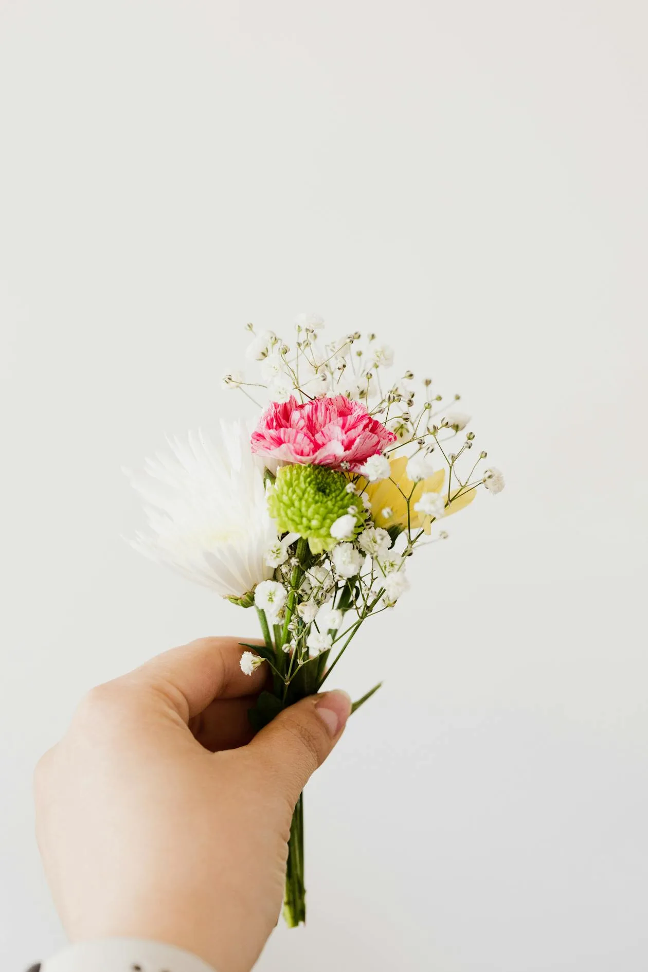 A woman holding a small and delicate bouquet of flowers