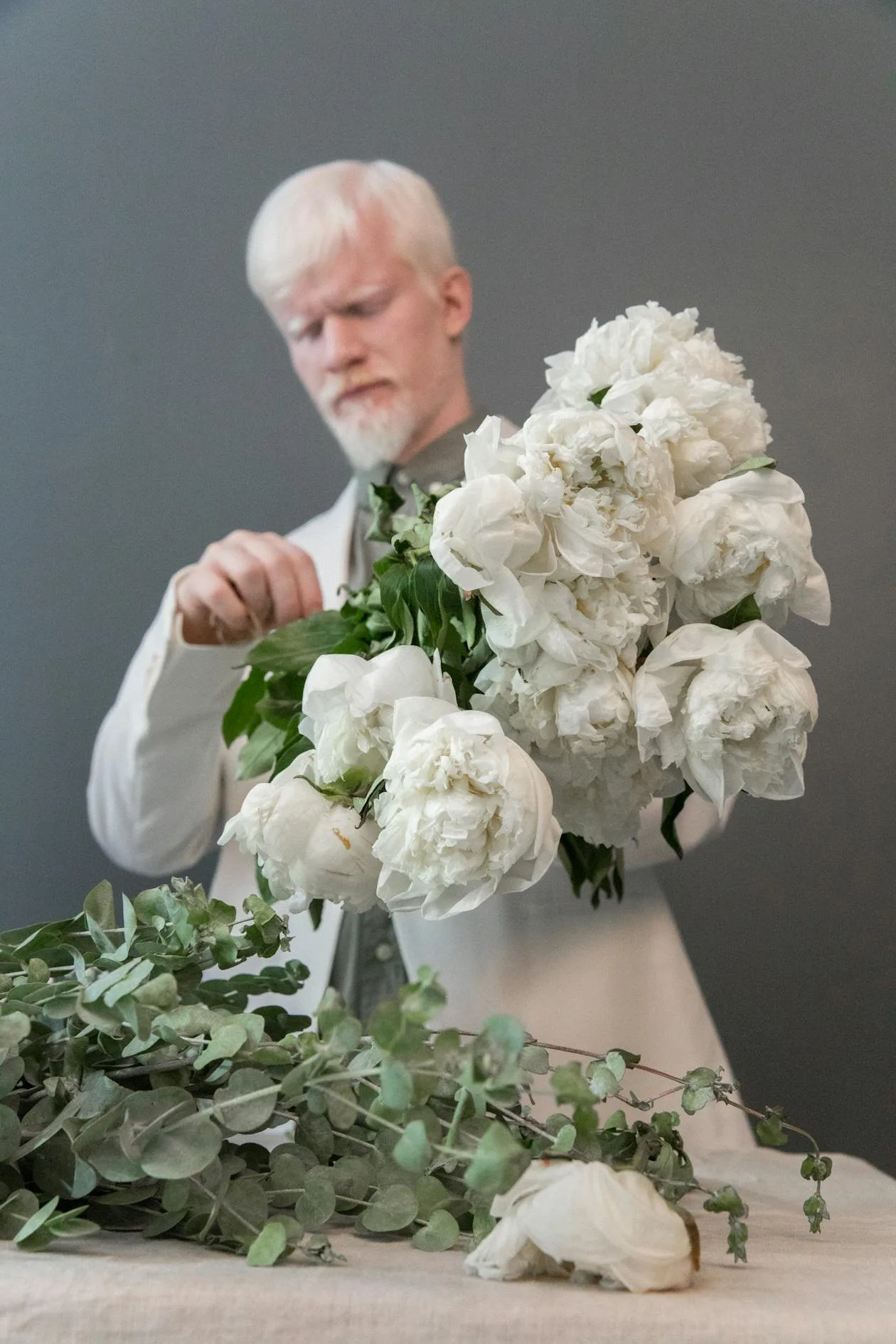 A man carefully arranging a bouquet of fresh white flowers