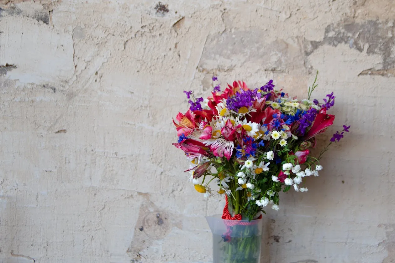 Loose colourful wildflower bouquet in a vase against a warm rustic background